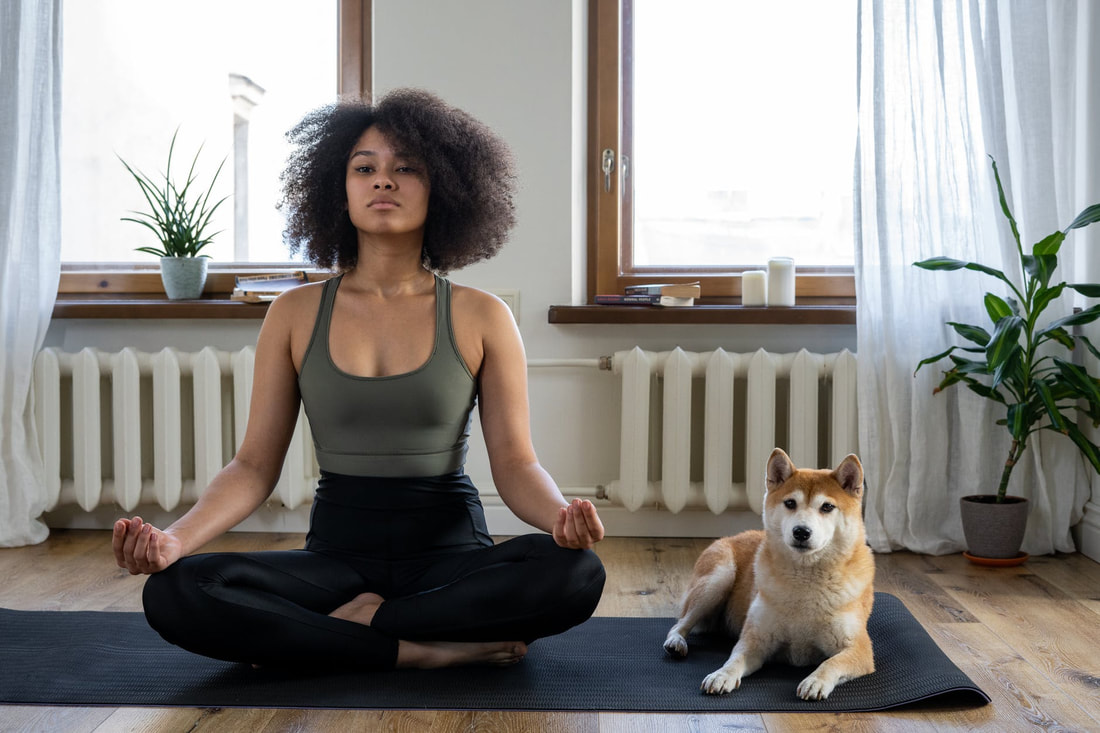 woman practicing yoga with dog by her side